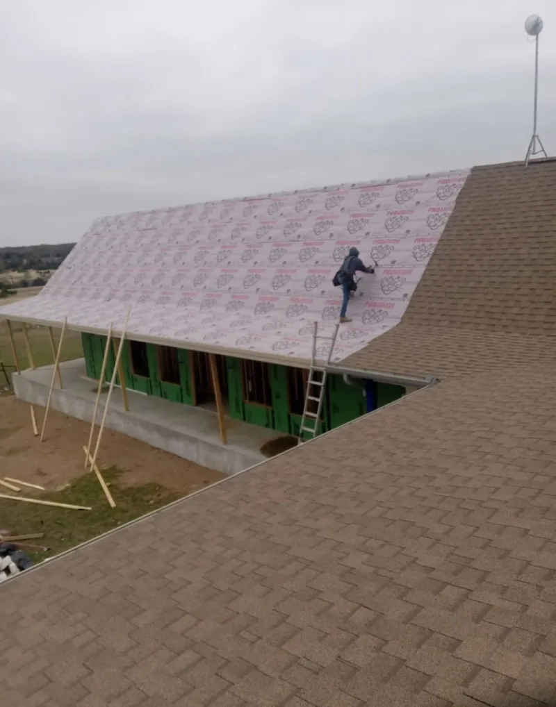 Worker preparing underlayment for a metal roof installation in Warwick